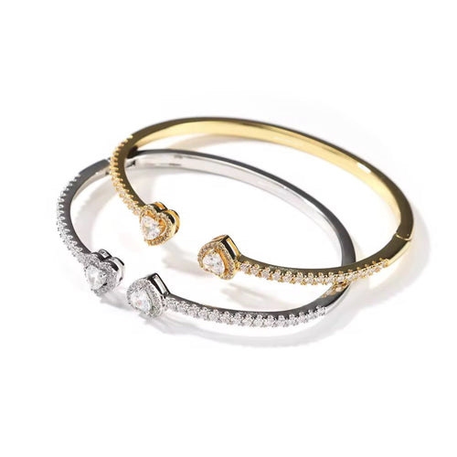 Two gold and silver bangles with diamond accents on a white background