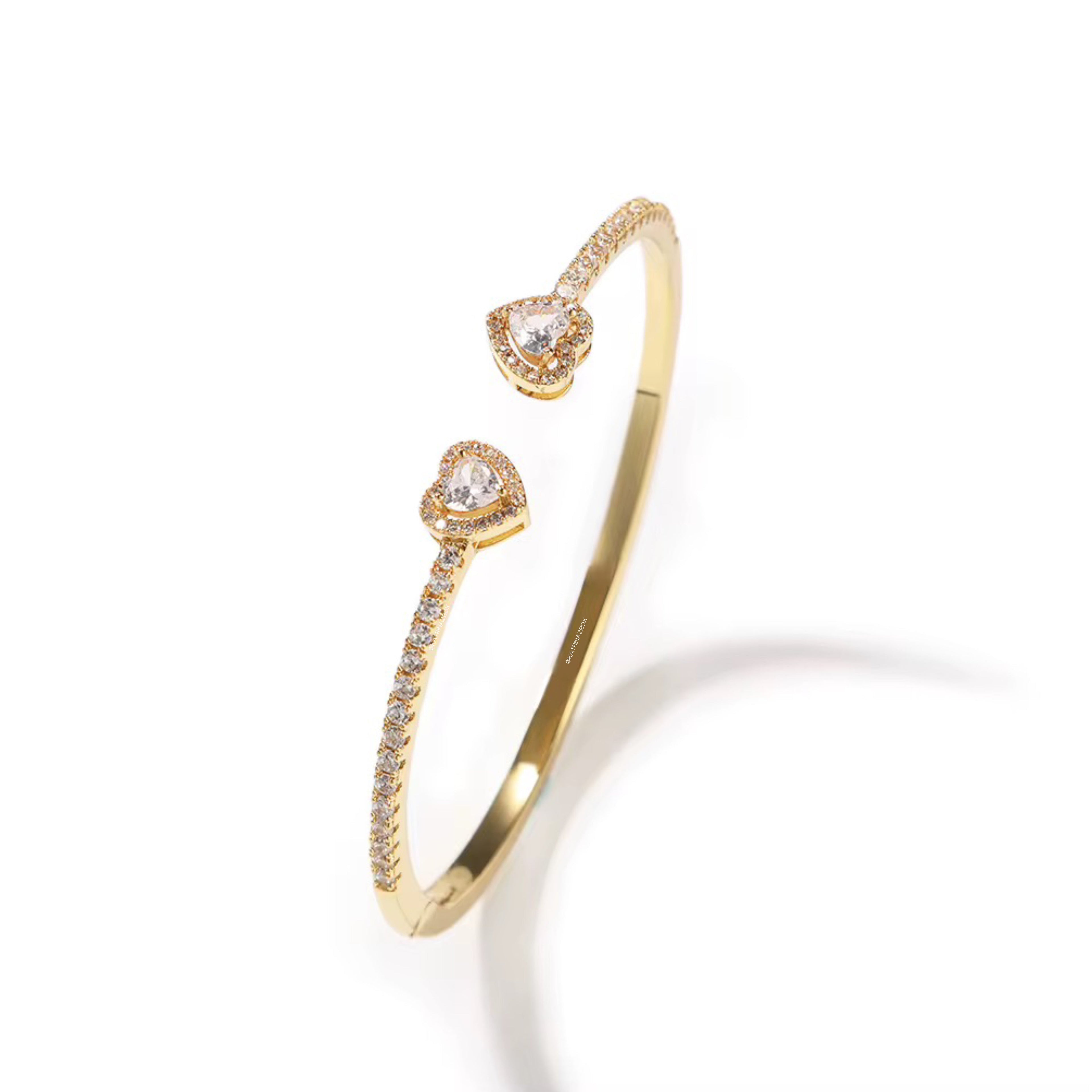 Gold bracelet with heart-shaped diamond accents on a white background
