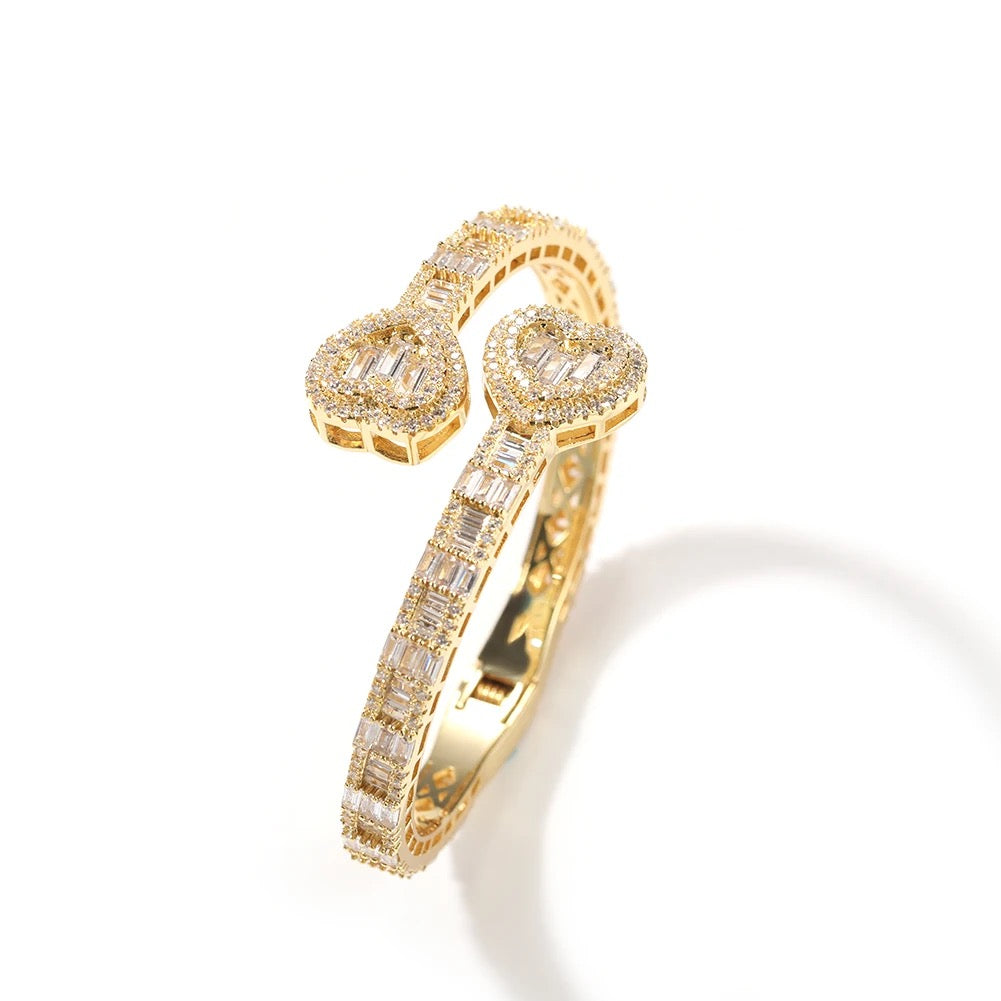 Gold heart baguette bangle with diamond accents on a white background